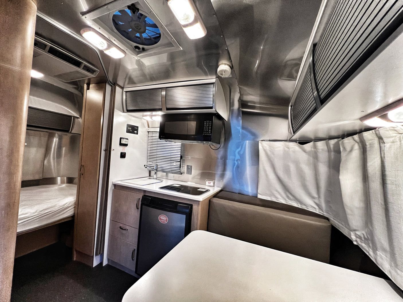 Inside a sleek RV rental, showcasing a compact kitchen, dining area, and cozy bed. Perfect for your next adventure.