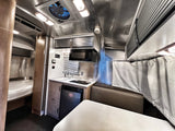 Inside a sleek RV rental, showcasing a compact kitchen, dining area, and cozy bed. Perfect for your next adventure.