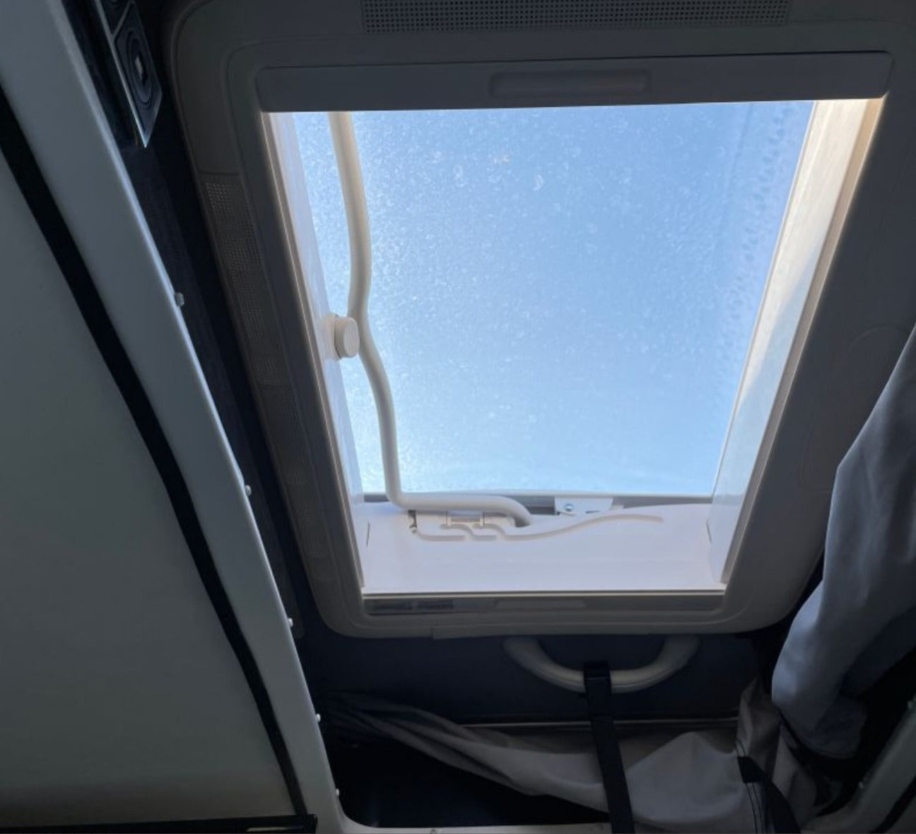 View up into an RV rental's open skylight, revealing bright blue sky. Natural light for your campervan adventures.