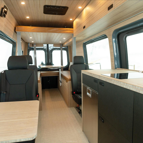 Bright RV rental interior with warm wood finishes, kitchen, sleek appliances & flexible seating.