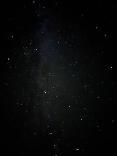 Bright, distorted lights from raindrops on an RV rental window at night.