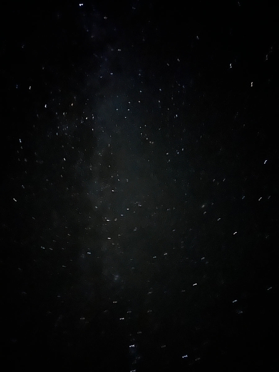 Bright, distorted lights from raindrops on an RV rental window at night.