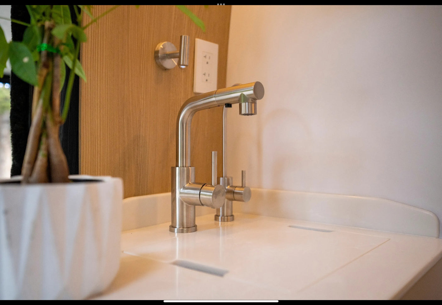 RV rental kitchen with a sleek stainless steel faucet, white countertop, and small green plant.