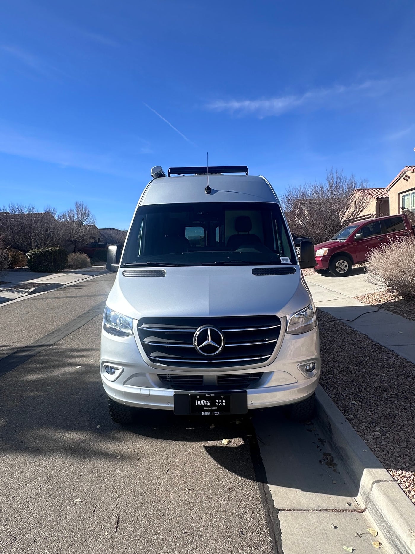  parked on a sunny residential street.|Silver Mercedes-Benz Sprinter van rv rental parked curbside on a sunny day