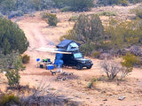 Off-grid camping with a custom "RV rental" alternative: Jeep, rooftop tent, campfire, and dog on a dirt road in the wilderness.