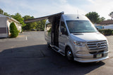 Silver Mercedes-Benz Sprinter RV rental van with an extended awning, parked on asphalt.