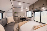 An inviting RV rental interior, showcasing a well-equipped kitchen, comfortable bed, and living area with scenic windows.