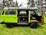 Vibrant green camper van RV rental, side open. Features ARB awning, ICECO cooler, and off-road tires for adventure.