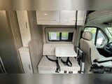 Interior of an RV rental: a beige dinette with removable table, overhead cabinets, and front passenger seat.