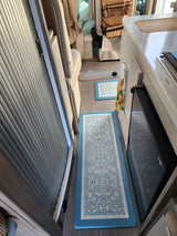 rv rental: Modern interior featuring a compact kitchenette, sleeping area, decorative blue floor mats, and tambour storage.