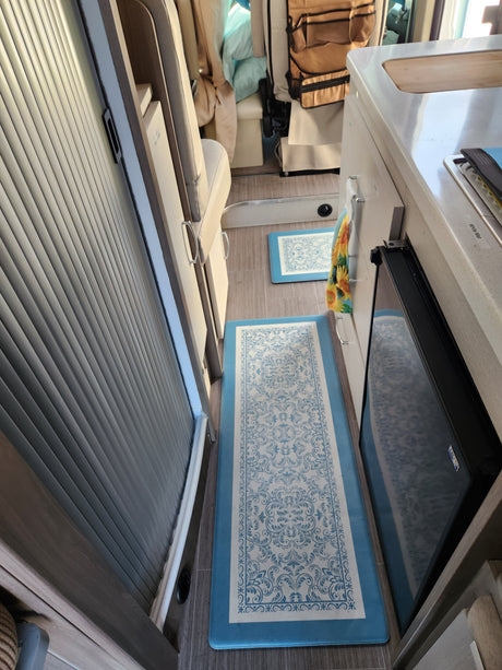 rv rental: Modern interior featuring a compact kitchenette, sleeping area, decorative blue floor mats, and tambour storage.