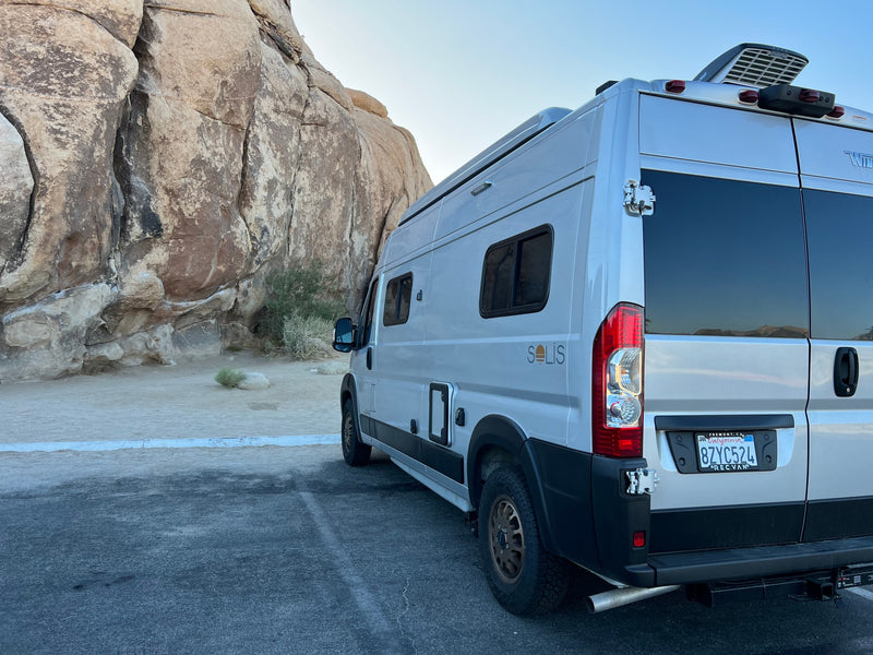 This rv rental Winnebago Solis camper van is parked by large desert rocks, ready for adventure. — photo 12