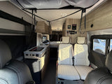 Interior of a modern RV rental: a well-equipped kitchenette, stylish seating, and a rear bed. Ready for your next road trip.
