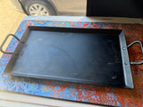 Lodge griddle on a vibrant mat, ready for cooking on your rv rental trip. View of RV window and tire.