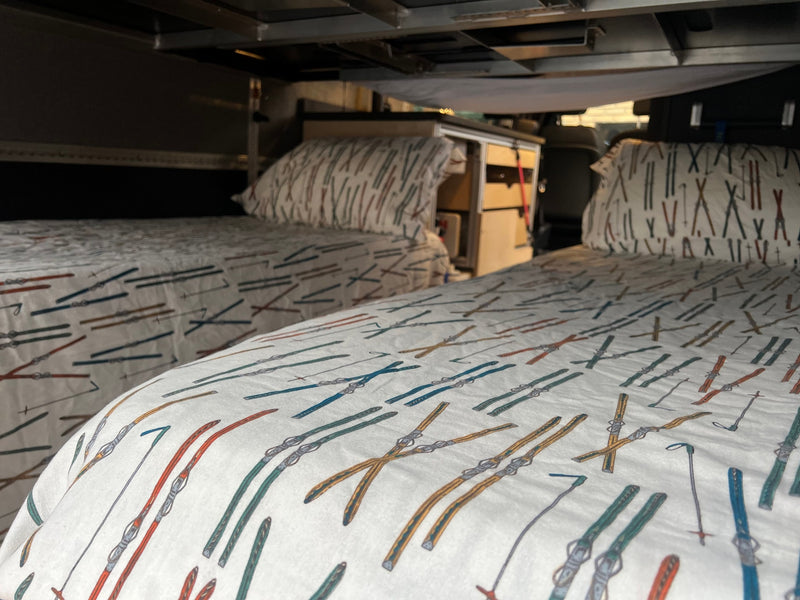 Cozy beds with vibrant ski-themed bedding in an RV rental, offering a comfortable, adventurous sleeping space. — photo 16