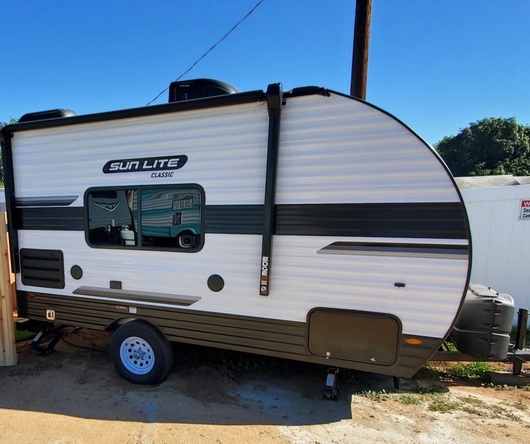 A white and dark grey Sun Lite Classic travel trailer, perfect for your next rv rental adventure, parked outdoors. — photo 2