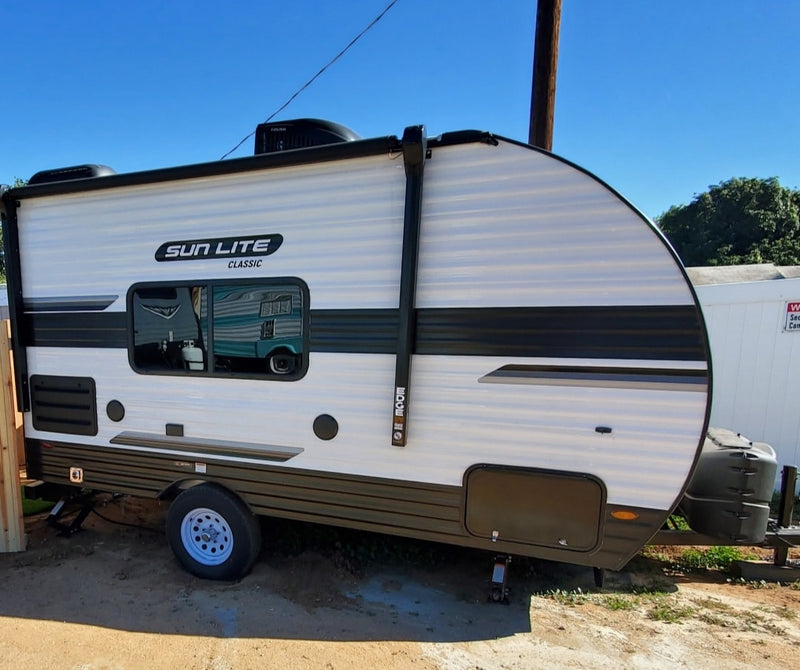 A white and dark grey Sun Lite Classic travel trailer, perfect for your next rv rental adventure, parked outdoors. — photo 2