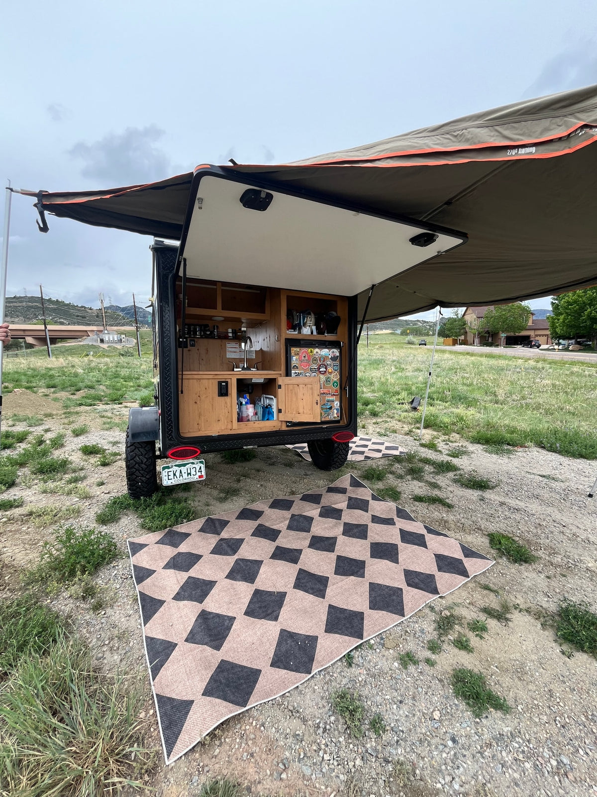 Enjoy your RV rental adventure! Small camper trailer with open kitchen, extended awning, and ground mat for easy outdoor living. — photo 10