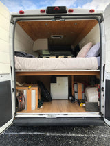 RV rental: Explore this DIY camper van interior, featuring a cozy bed, water tanks, and power setup.