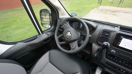Inside an RV rental, featuring the driver's cockpit: steering wheel with Ram logo, dashboard, and infotainment system.
