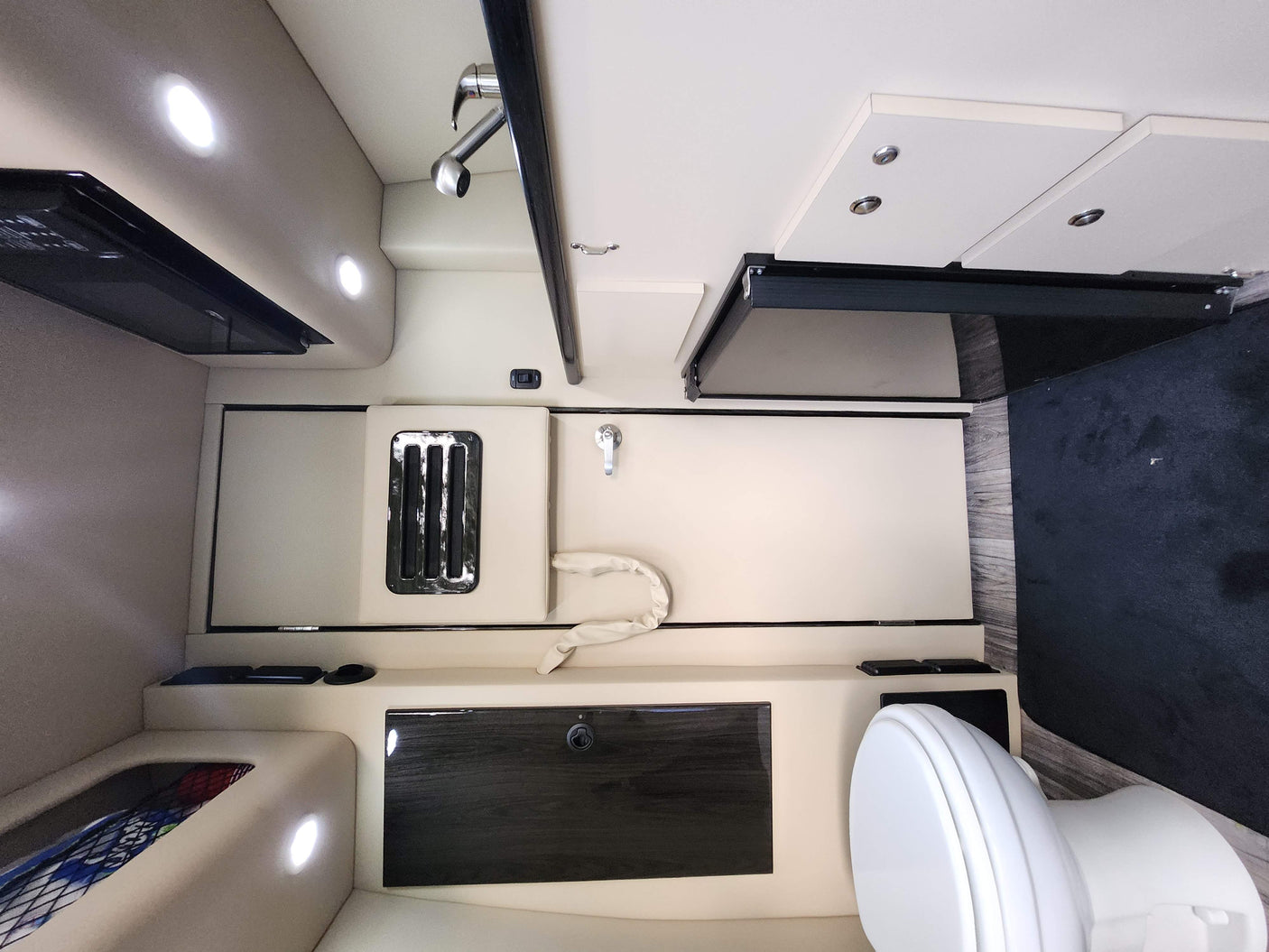 RV rental interior: compact kitchen with microwave, bathroom with toilet & shower, plus seating/bed area and storage.