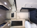RV rental interior: compact kitchen with microwave, bathroom with toilet & shower, plus seating/bed area and storage.