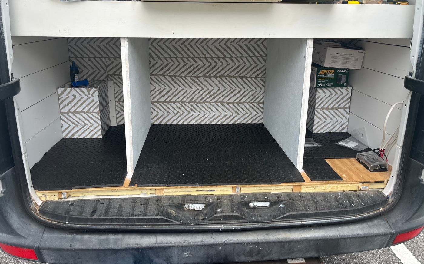 RV rental van's custom interior: organized cargo space with chevron walls, rubber mats, built-in storage, and power system setup. — photo 4