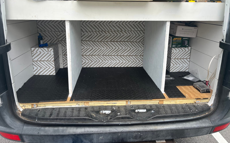 RV rental van's custom interior: organized cargo space with chevron walls, rubber mats, built-in storage, and power system setup. — photo 4