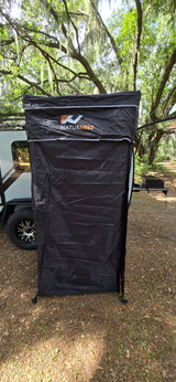 NATURNEST privacy shelter attached to an RV rental, providing outdoor changing or showering space in a wooded campsite.