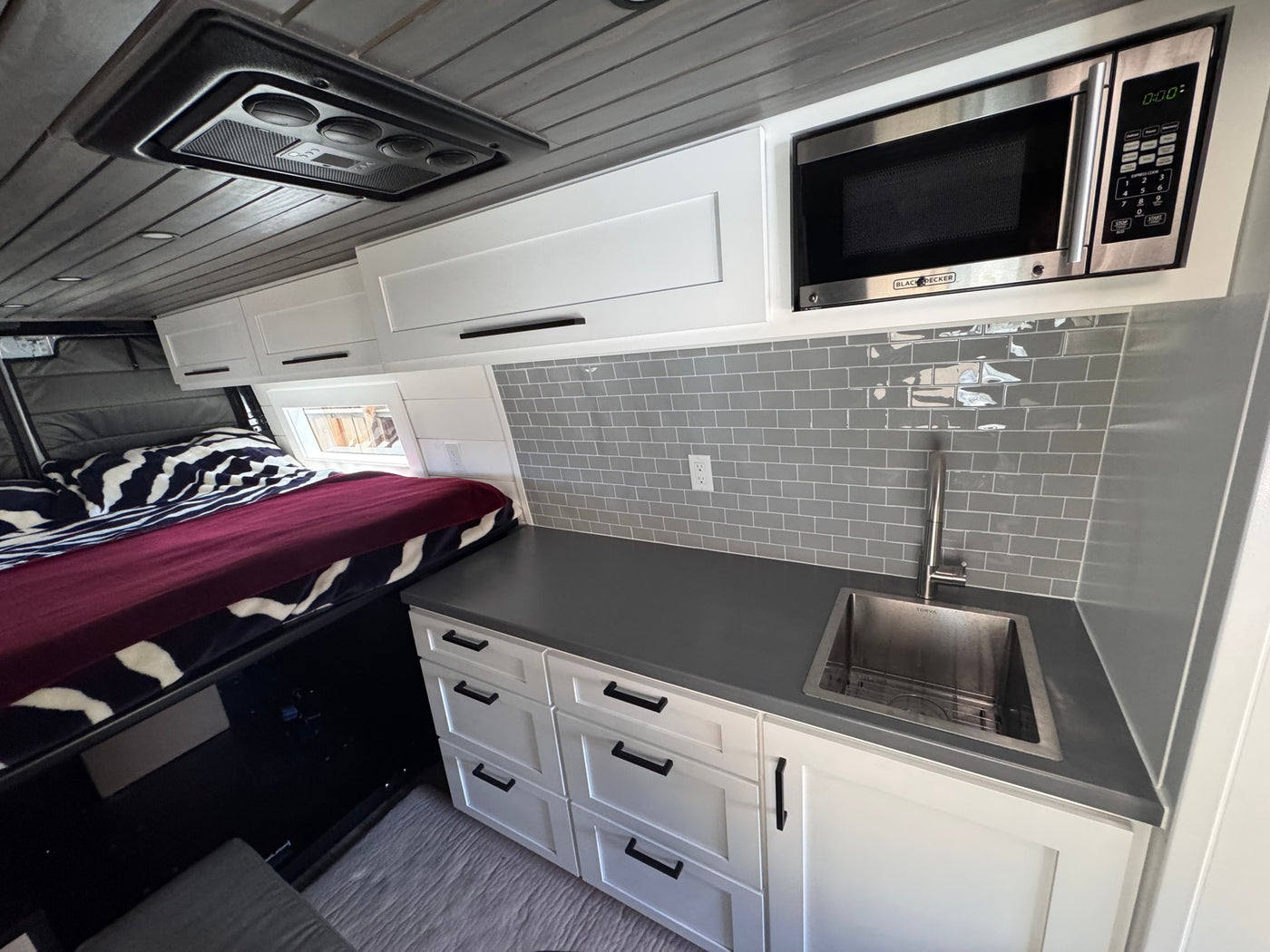  and two mountain bikes stored in the lower garage of a grey camper van.|Scenic RV rental adventure: a camper van nestled on a dirt path — photo 13