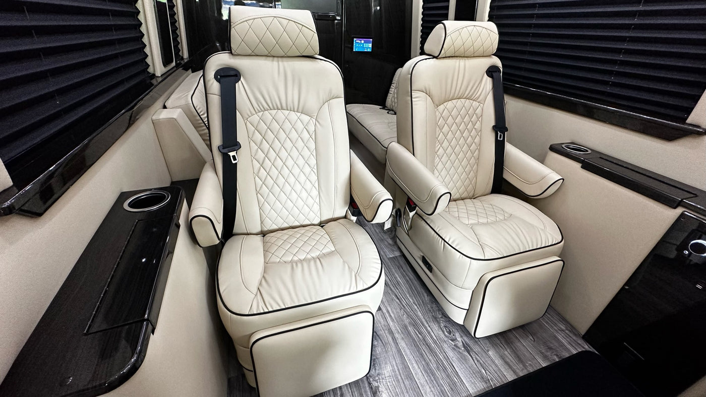 Inside a spacious RV rental: cream leather captain's chairs with diamond quilting, footrests, and dark wood trim details. — photo 14