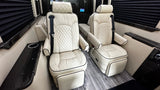 Inside a spacious RV rental: cream leather captain's chairs with diamond quilting, footrests, and dark wood trim details.