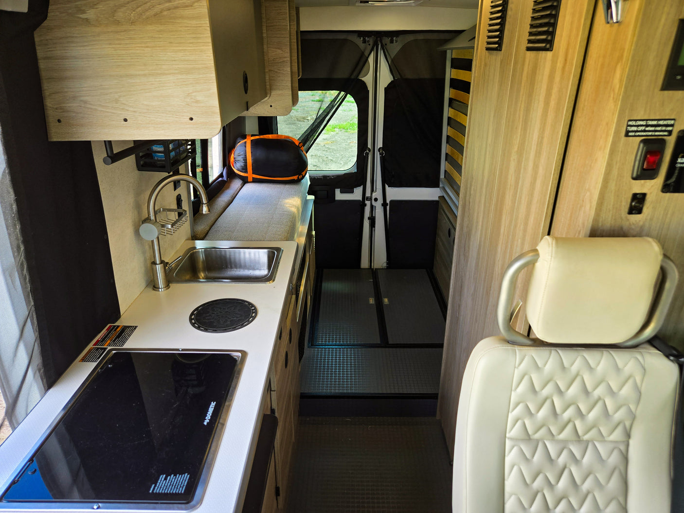 RV rental interior: A compact living space featuring a kitchen with sink, Dometic stovetop, and seating/bed area.