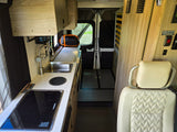 RV rental interior: A compact living space featuring a kitchen with sink, Dometic stovetop, and seating/bed area.
