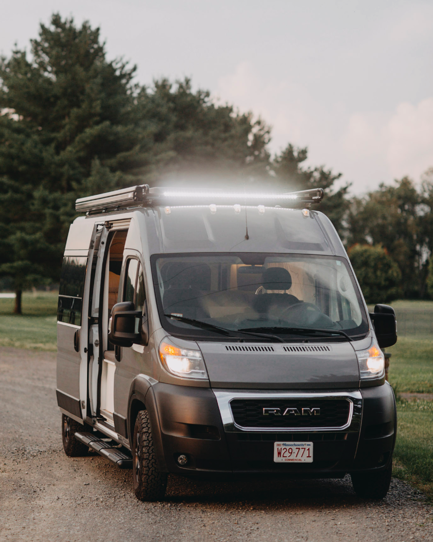 A gray Ram ProMaster camper van with bright roof lights, ready for an RV rental adventure. Perfect road trip vehicle.