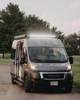 A gray Ram ProMaster camper van with bright roof lights, ready for an RV rental adventure. Perfect road trip vehicle.