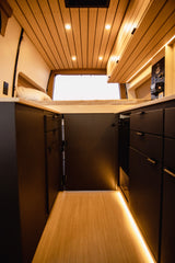 Explore a cozy RV rental interior, featuring a comfortable bed, smart storage, and warm wooden accents.