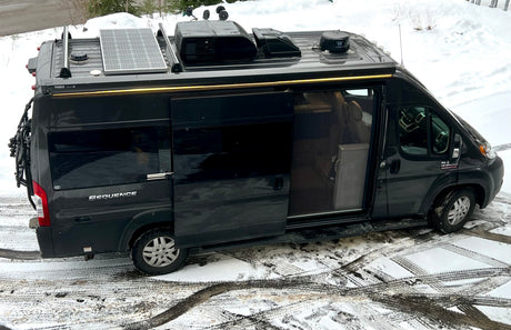 Sleek dark gray RV rental camper van, equipped for adventures with solar panels, AC, and a bike rack.