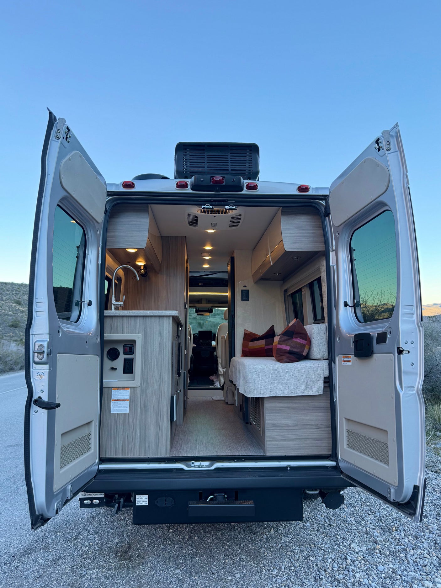 Open doors reveal a modern **rv rental** camper van interior: kitchen, bed, and mobile amenities for your next road trip adventure.