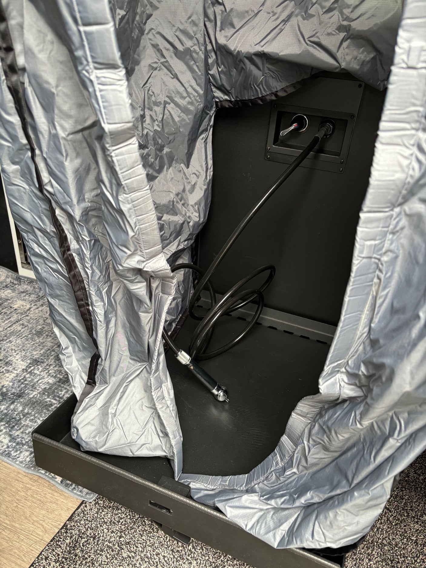 RV rental setup: internal equipment showing cable connections & a silver protective cover in a compartment.