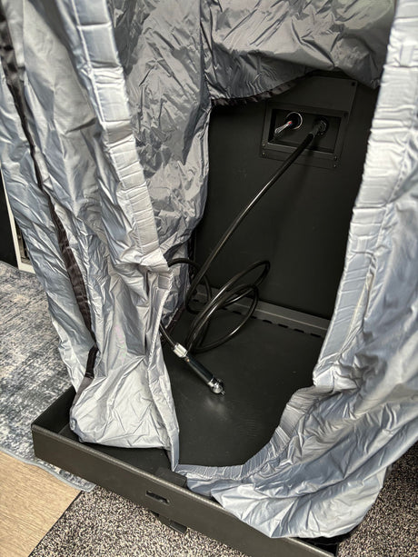 RV rental setup: internal equipment showing cable connections & a silver protective cover in a compartment.