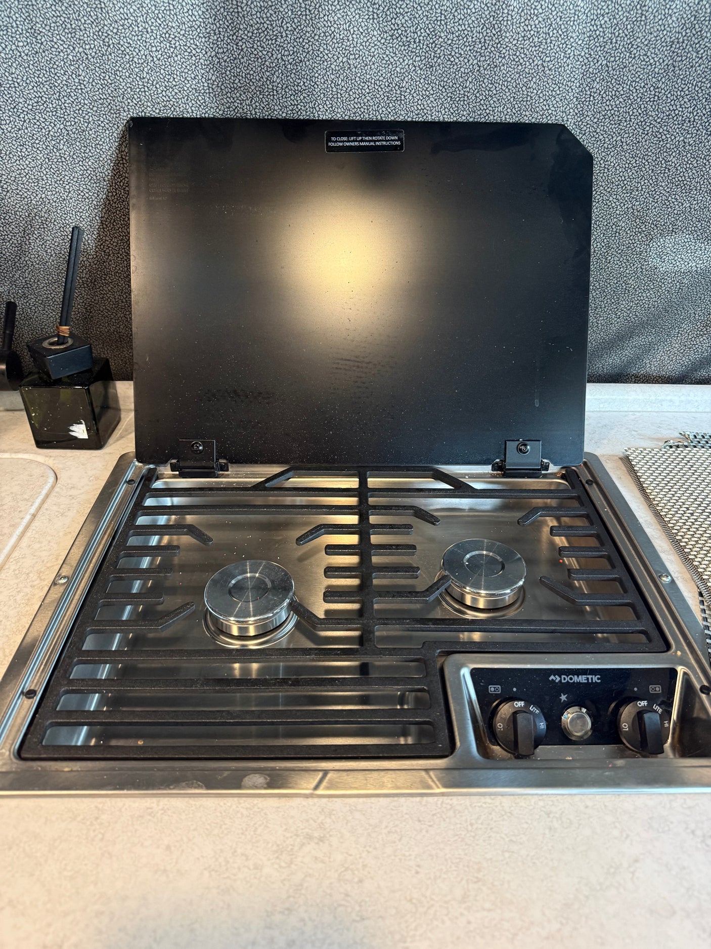 Dometic 2-burner RV cooktop in an rv rental, with its black glass lid open, ready for use.