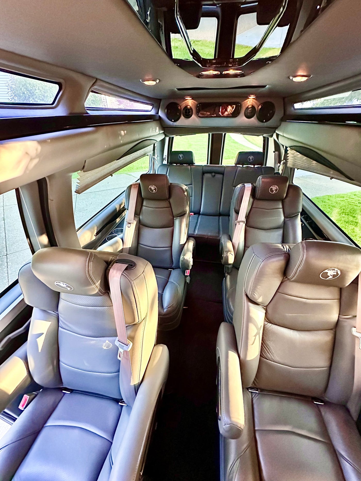  parked on a driveway next to a brick house and tree.|Experience comfort in this RV rental! Interior view of a spacious van — photo 3