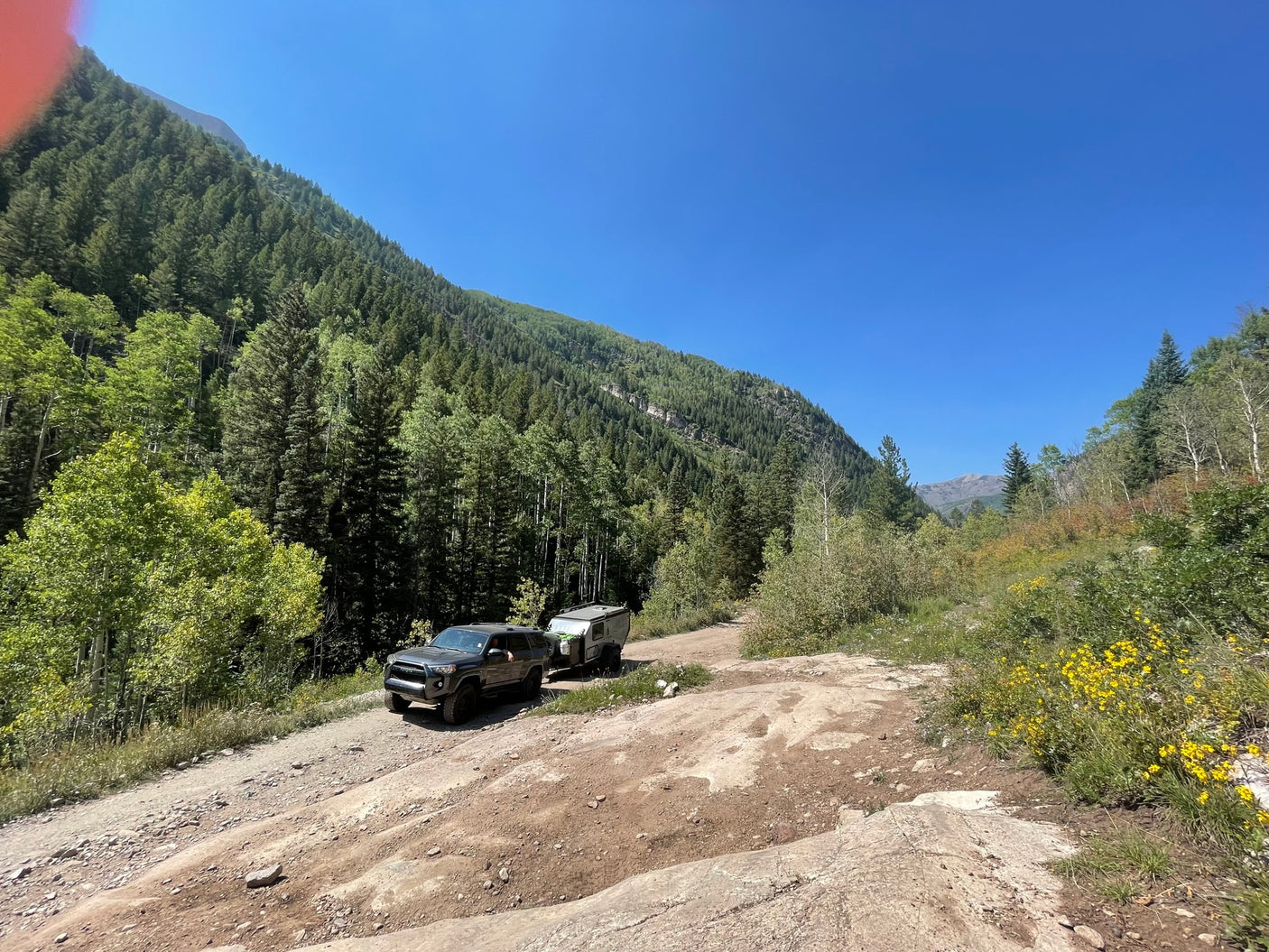  on a wet driveway. Suburban homes and vehicles visible.|This rugged overland RV rental
