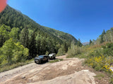  on a wet driveway. Suburban homes and vehicles visible.|This rugged overland RV rental