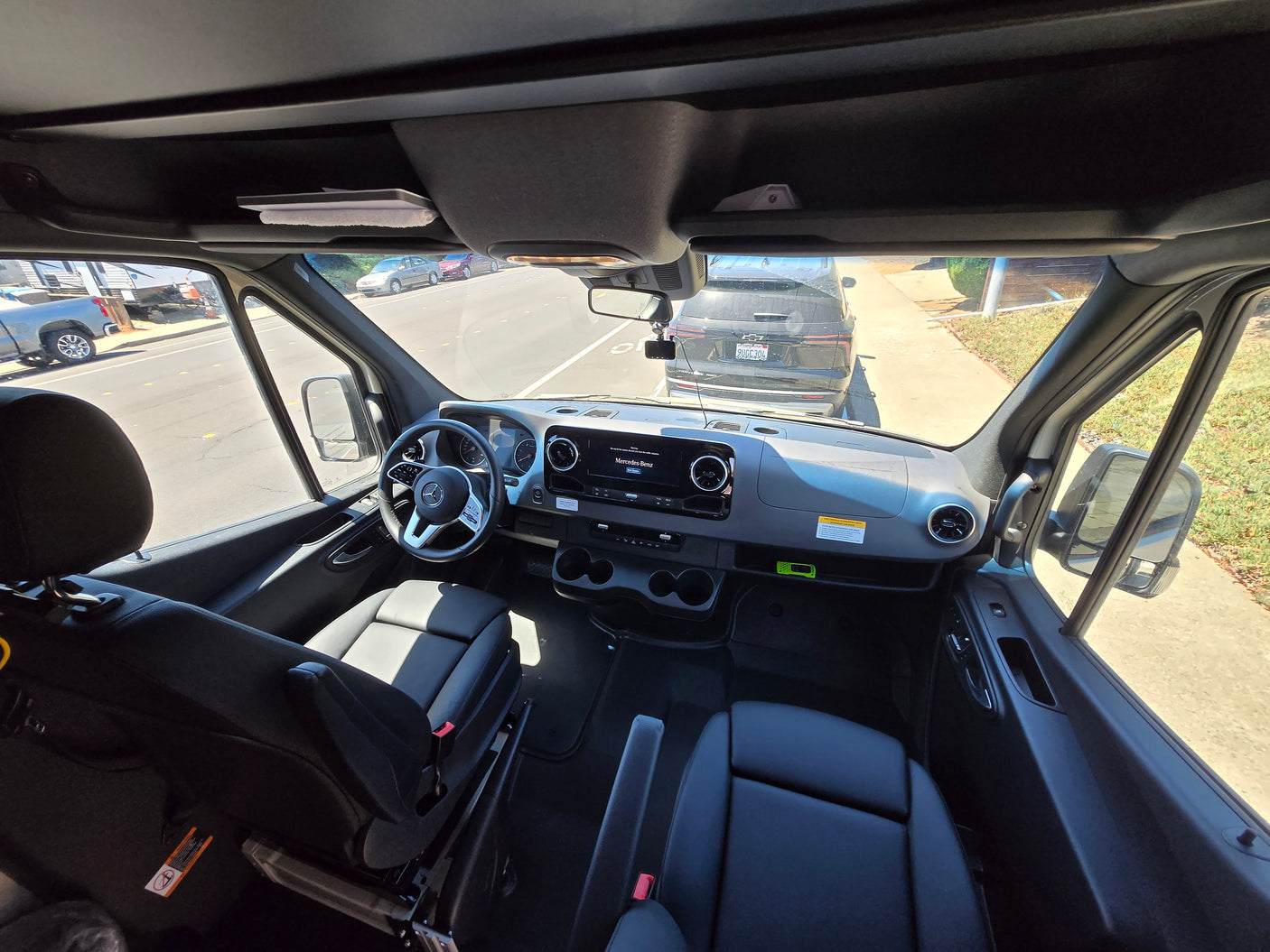 Inside a modern Mercedes-Benz Sprinter van, showing the cockpit and front seats, ready for RV rental.