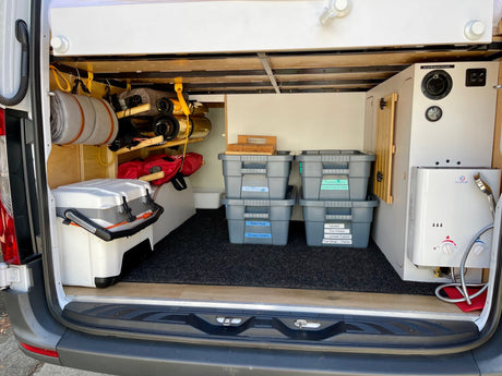 Explore with ease! Organized RV rental storage shows bins labeled for gear, cooler, and a water heater setup.