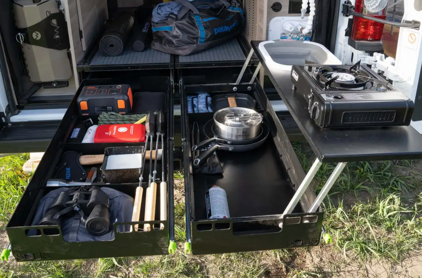 This rv rental features an organized pull-out camping kitchen with stove, sink, and gear storage for van life adventures.