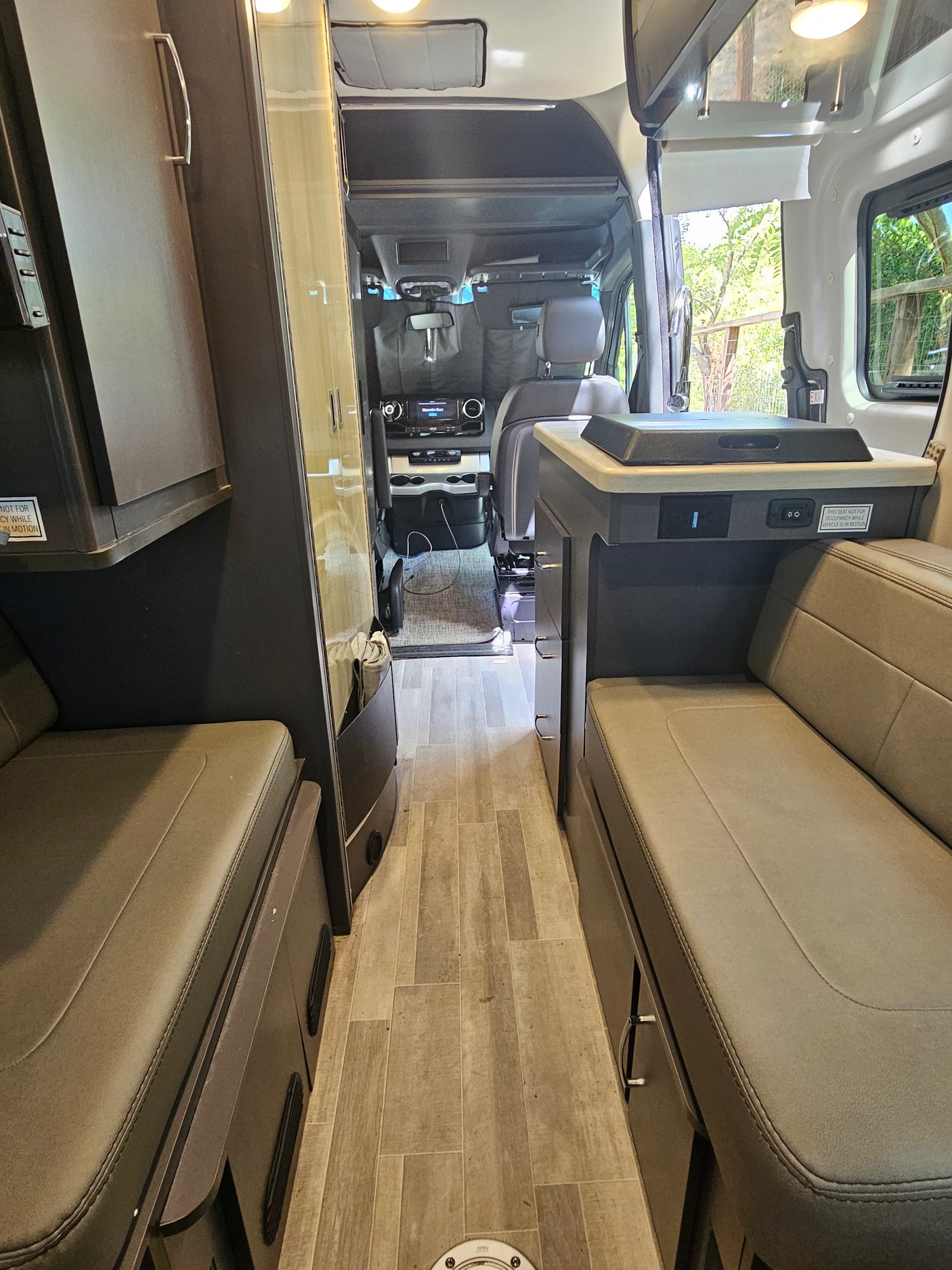 Spacious RV rental interior, showing comfortable seating, a central aisle, and the front cockpit area.