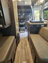 Spacious RV rental interior, showing comfortable seating, a central aisle, and the front cockpit area.